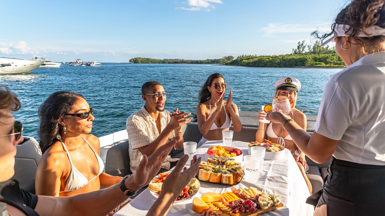 A group of friends spending a sunny afternoon on Extasy Yacht in front of a huge table spread of delicious catering as cocktails are being served